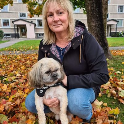 Marie Persson tillsammans med liten hund sitter på huk bland höstlöv.